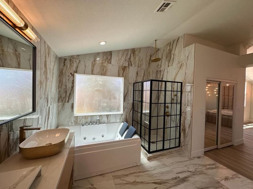 Modern bathroom featuring a marble design, freestanding tub, and glass shower enclosure.
